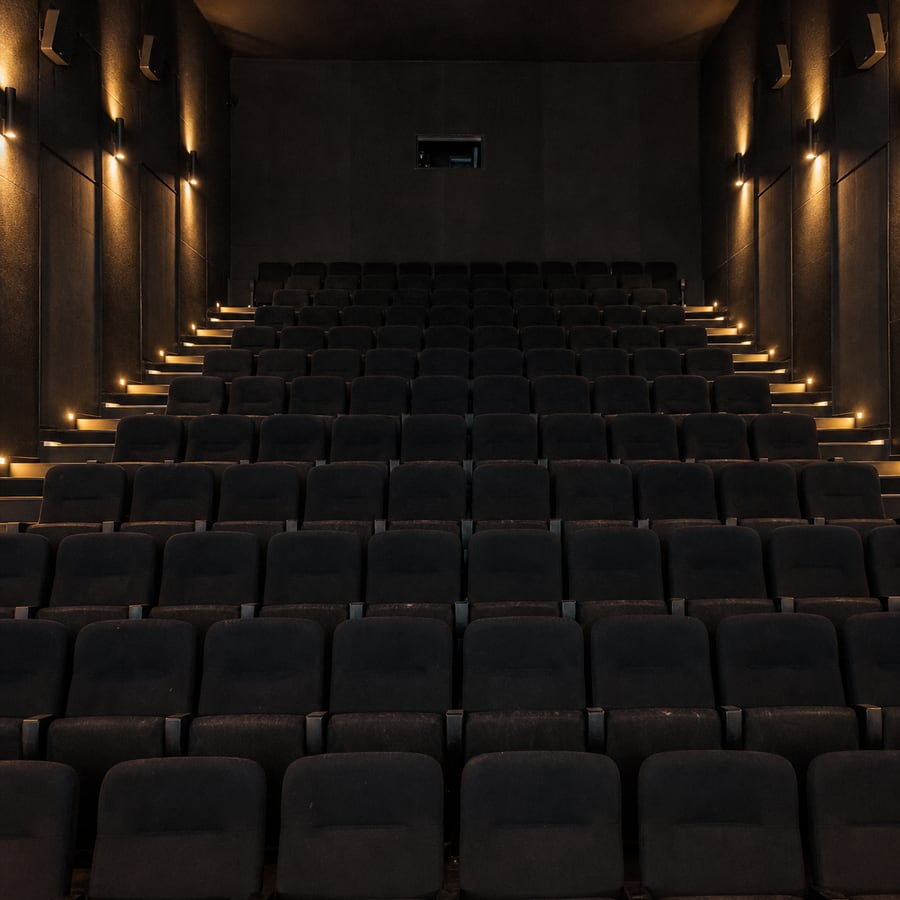 An empty independent cinema auditorium, house lights half up.